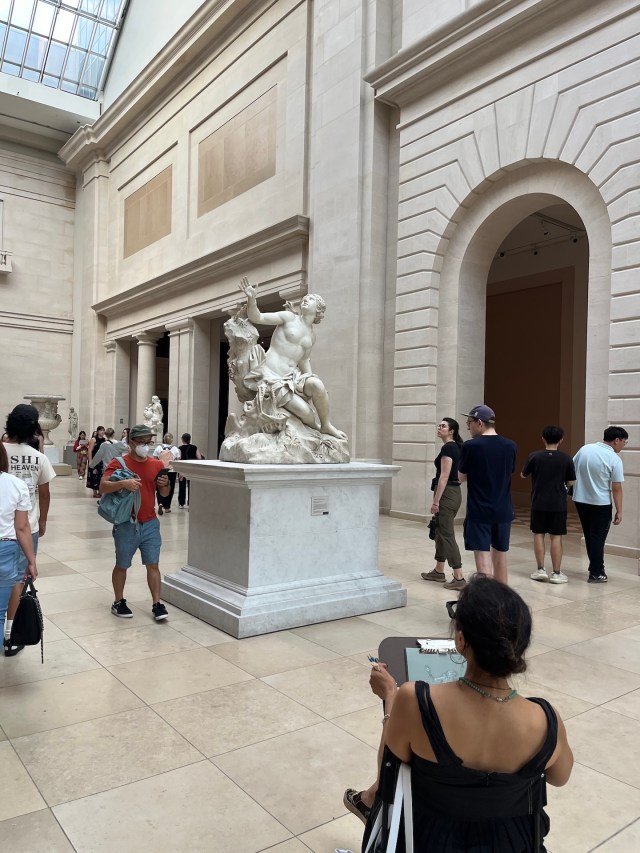 A woman sketching the same sculpture at the met